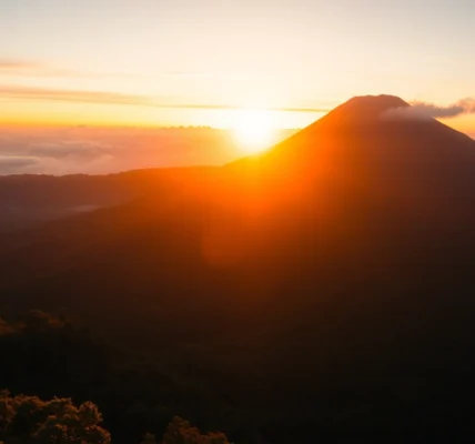 Hikers admiring the stunning view of Mt. Rinjani's active volcano peak on a clear day, emphasizing adventure and natural beauty.